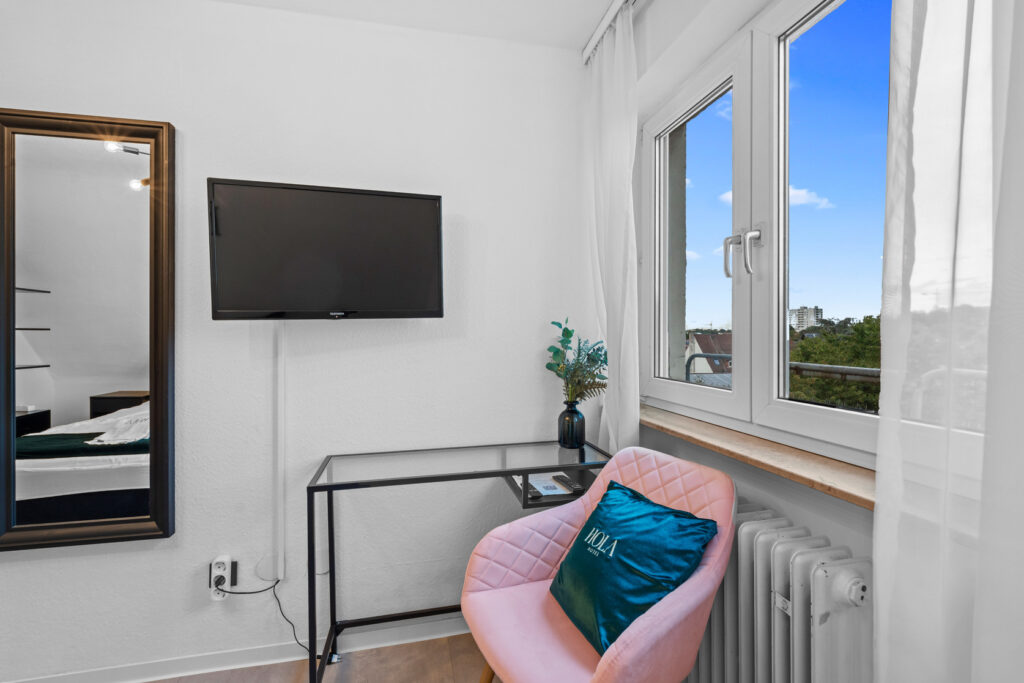 Fernseher und Sitzbereich im Hotelzimmer des Hola Hotel Stuttgart Zuffenhausen.